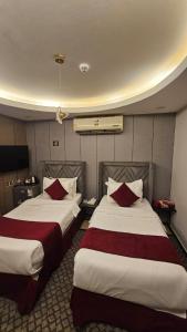 a hotel room with two beds with red pillows at اصداء الراحة للشقق المخدومة 3 in Riyadh +7 photos