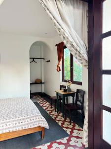 a bedroom with a bed and a table and a window at Anio Ha Giang Hotel in Ha Giang