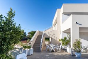 a white house with stairs and tables and chairs at Helianthus in Cisternino