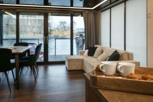 a living room with a couch and a table with mugs at Domy Na Wodzie La Mare Houseboats Bydgoszcz in Bydgoszcz