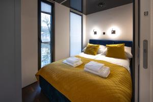 a bedroom with a bed with yellow sheets and yellow pillows at Domy Na Wodzie La Mare Houseboats Bydgoszcz in Bydgoszcz