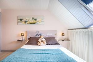 a teddy bear sitting on a bed in a bedroom at Ty Annick chambres d'hôtes in Névez