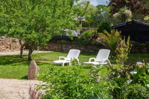 three white chairs sitting in the grass in a garden at Ty Annick chambres d'hôtes in Névez
