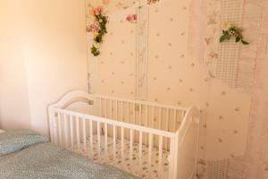 a white crib in a bedroom with flowers on the wall at Anuskina kuca in Pakovrače