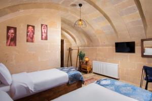 a bedroom with two beds and a tv in a room at Cappadocia Tughan Stone House in Uçhisar