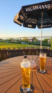 Zwei Biergläser stehen auf einem Tisch mit einem Sonnenschirm. in der Unterkunft MBar in Altnau