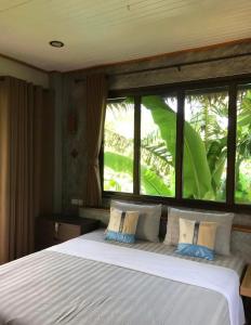a bedroom with a large white bed with windows at Thai Terrace Bungalow in Thong Nai Pan Yai