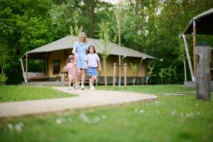 a woman and two girls walking down a path in front of a house at Urban Gardens Gent in Ghent