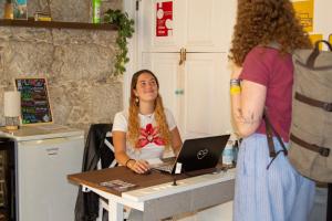 a woman sitting at a table with a laptop at Onefam Clerigos in Porto