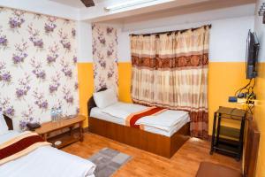 a small room with two beds and a window at Tokyo Hotel in Kathmandu