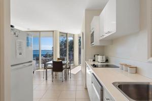 a kitchen with white appliances and a table with chairs at Mirage 1 24 Gloucester Street in Nelson Bay +22 photos