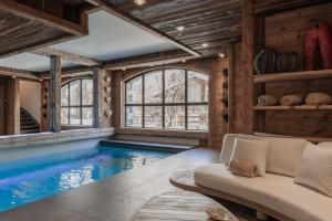 an indoor pool in a house with a couch at Chalet Face - LES CHALETS COVAREL in Val-d'Isère