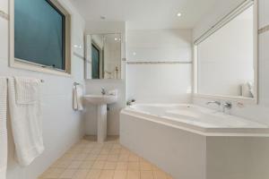 a white bathroom with a tub and a sink at Mirage 1 24 Gloucester Street in Nelson Bay