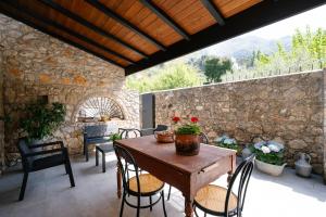 a patio with a table and chairs and a stone wall at Case Vacanza Baglio Ciambre in Borgetto