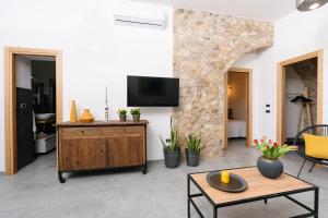 a living room with a tv on a stone wall at Case Vacanza Baglio Ciambre in Borgetto