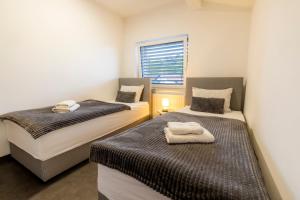 two beds in a small room with a window at Luxury Family Apartment with Terrace FRIGO in Maribor