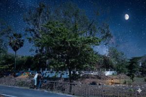 a man standing next to a fence at night at Hotel The Mount View in Rājgīr
