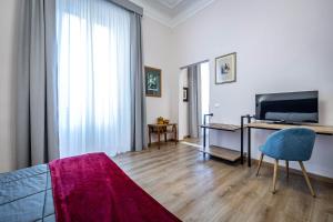 a living room with a bed and a desk with a television at Five Suites Mantellate 9 in Florence
