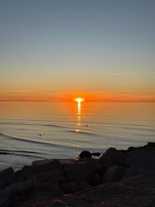 a sunset on the beach with the sun setting over the water at Apartament Perełka in Darłowo