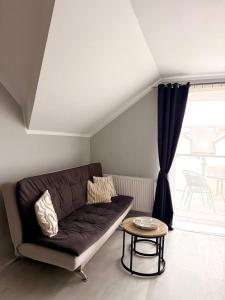 a living room with a brown couch and a table at Apartament Perełka in Darłowo +10 photos