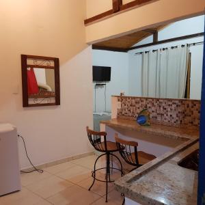 a kitchen with two chairs and a counter with a mirror at Pouso Bem Estar in Tiradentes