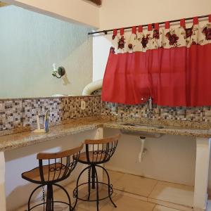 a kitchen with a red curtain and two bar stools at Pouso Bem Estar in Tiradentes