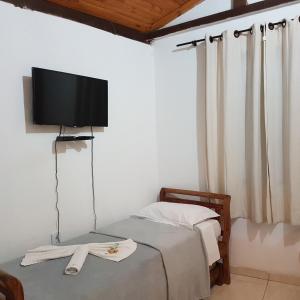 a bedroom with a bed with a flat screen tv on the wall at Pouso Bem Estar in Tiradentes