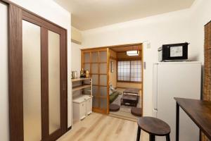 a kitchen with a refrigerator and a table and a stool at 暖迎の宿 in Tokyo