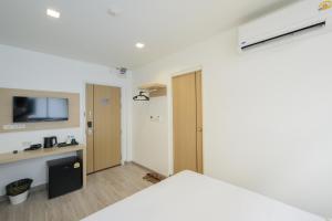 a room with a bed and a tv on a wall at Global Hotel Pratunam Bangkok in Bangkok