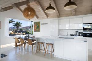 a kitchen with white cabinets and a table with stools at Villa Liquen in Yaiza