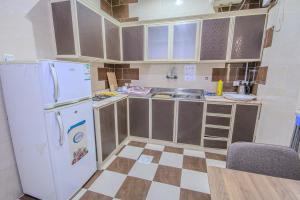 a small kitchen with white appliances and a checkered floor at صدي للشقق المخدومة in Khamis Mushayt