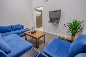 a living room with blue couches and a tv at صدي للشقق المخدومة in Khamis Mushayt
