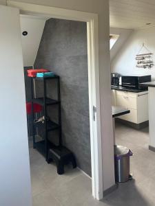 a kitchen with a shelf in the corner of a room at de Zeester in Bredene-aan-Zee +6 photos