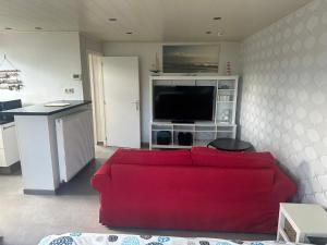 a living room with a red couch and a tv at de Zeester in Bredene-aan-Zee