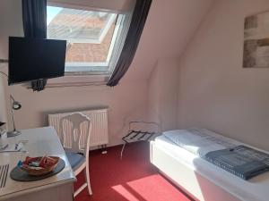 a small room with a bed and a desk and a tv at Hotel Hirsch in Sinsheim