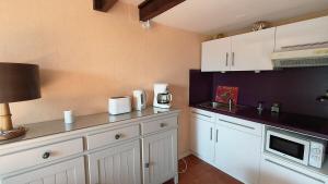 a kitchen with white cabinets and a microwave at Appartement du Port Neuf in Lanton