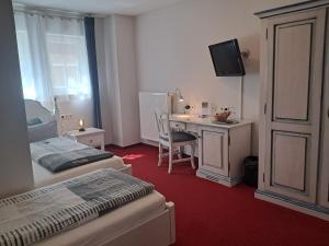 a hotel room with two beds and a desk with a television at Hotel Hirsch in Sinsheim