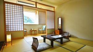 a room with a table and chairs and a window at ホテル秘境の湯 in Miyoshi