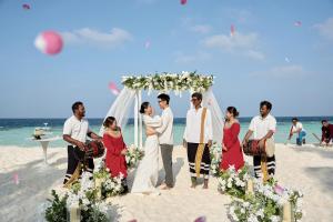 a group of people standing under a wedding arch on the beach at Eri Maldives in North Male Atoll +74 photos