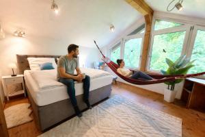 a man and woman sitting in a hammock in a bedroom at Rost Apartments - Design Ferienhaus mit Kamin und Hängematte in Laufen