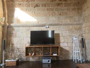 a living room with a television on a stone wall at Ermita de la Tuda-Villaescusa de las Torres in Villaescusa de las Torres +16 photos