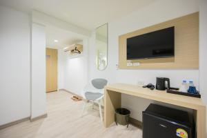 a room with a desk and a tv on a wall at Global Hotel Pratunam Bangkok in Bangkok