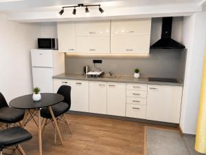 a kitchen with white cabinets and a table and chairs at M3-Apartmány in Martin