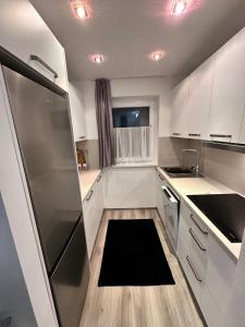 a kitchen with white cabinets and a black rug on the floor at Hiška Orel Terme Čatež in Čatež ob Savi +10 photos