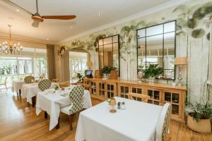 a restaurant with white tables and chairs and a mirror at Highlands House in Harare