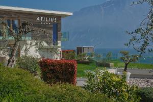 a building with a sign that reads atolis with the ocean in the background at Hotel Atilius - Adults Only in Limone sul Garda