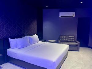 a bedroom with a large white bed and a chair at morph Bangkok Hotel in Bangkok