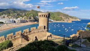 a castle next to a beach with boats in the water at Apartamento Tossa in Tossa de Mar