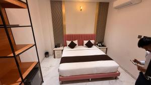 a bedroom with a bed and a person looking at a cell phone at Hotel Rosewood in Prayagraj