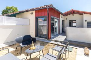 a patio with chairs and tables in front of a building at Cozy Cottage with Spa - Welkeys in Moliets-et-Maa